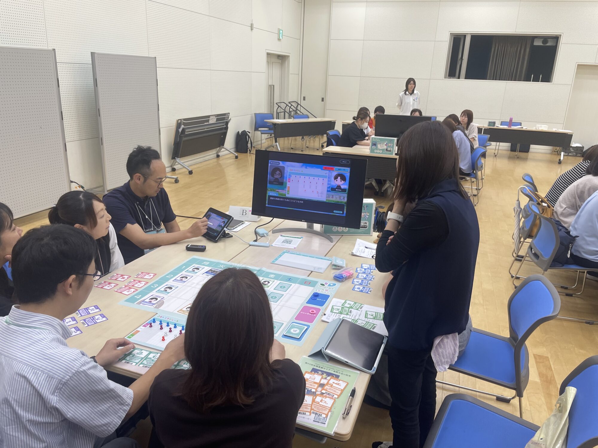 ボードとiPadを囲んでチームで24時間スケジュールを検討する研修の様子